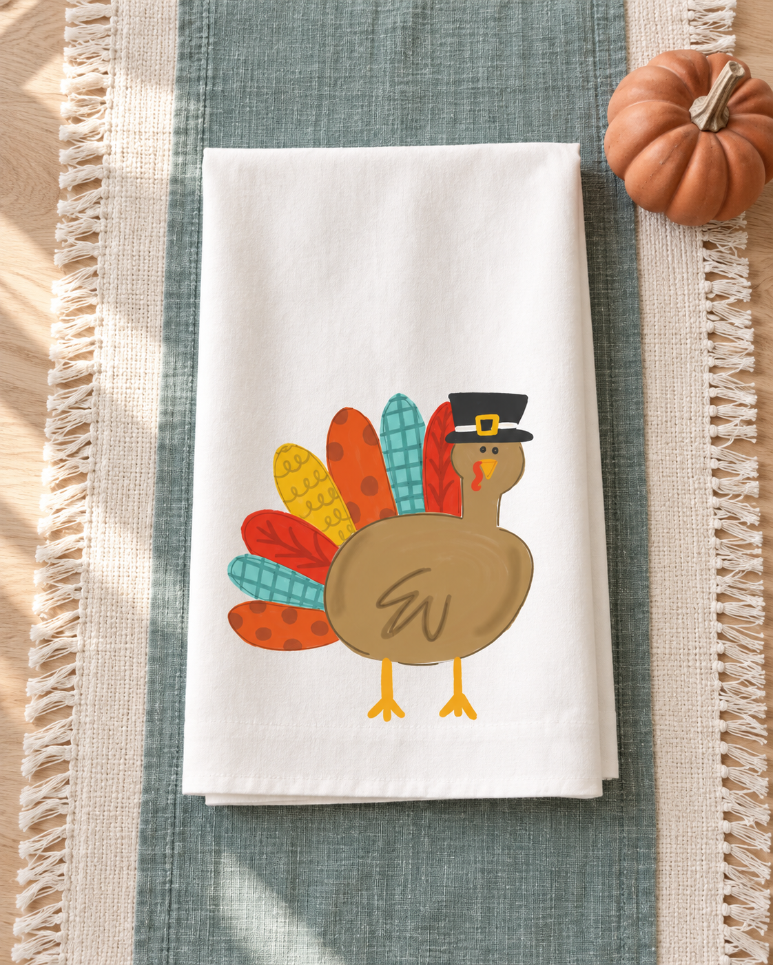 Patchy the Turkey Tea Towel styled on a muted teal Thanksgiving table runner